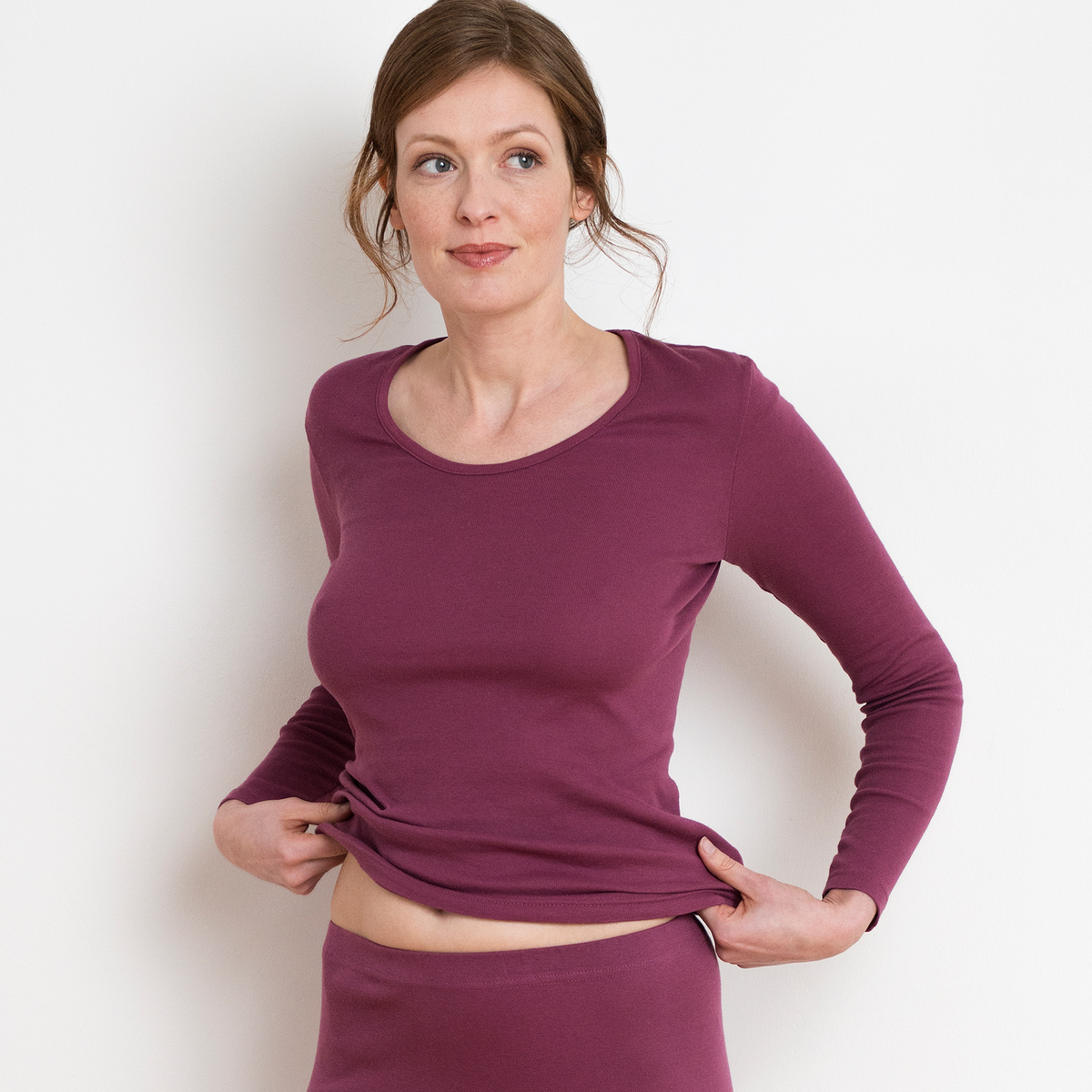 Women's organic cotton thermal long sleeve t-shirt in Dark Rose, model holding the hem