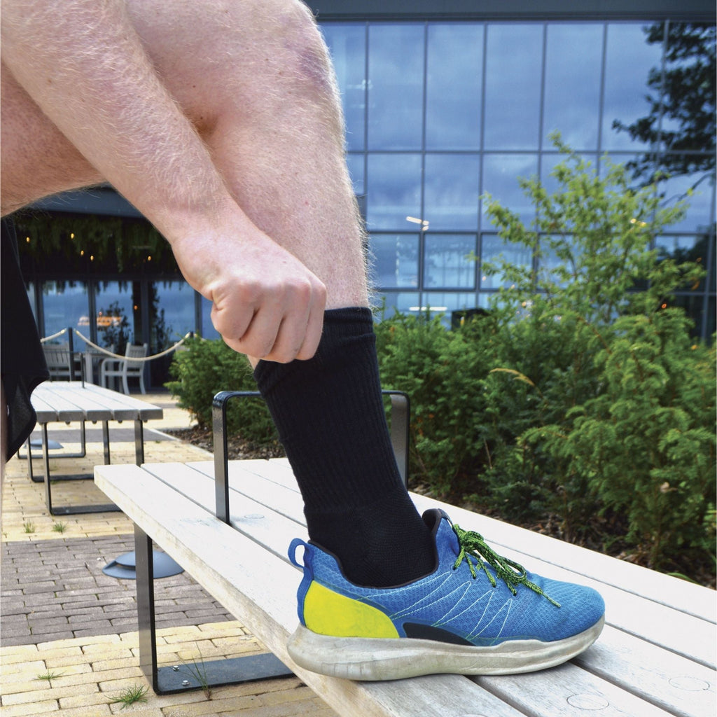 Men's bamboo running socks in Black, close-up worn with a running shoe