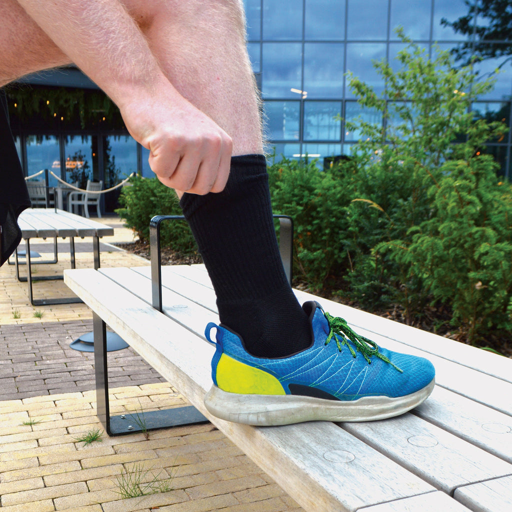 Men's bamboo running socks in Black, close-up worn with a running shoe