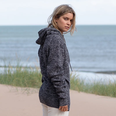Woman wearing the knitted recycled hoodie on a beach, side view