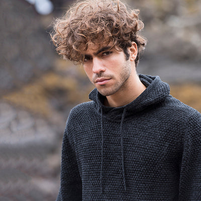 Close-up of a man wearing the knitted recycled hoodie in Charcoal/ Black