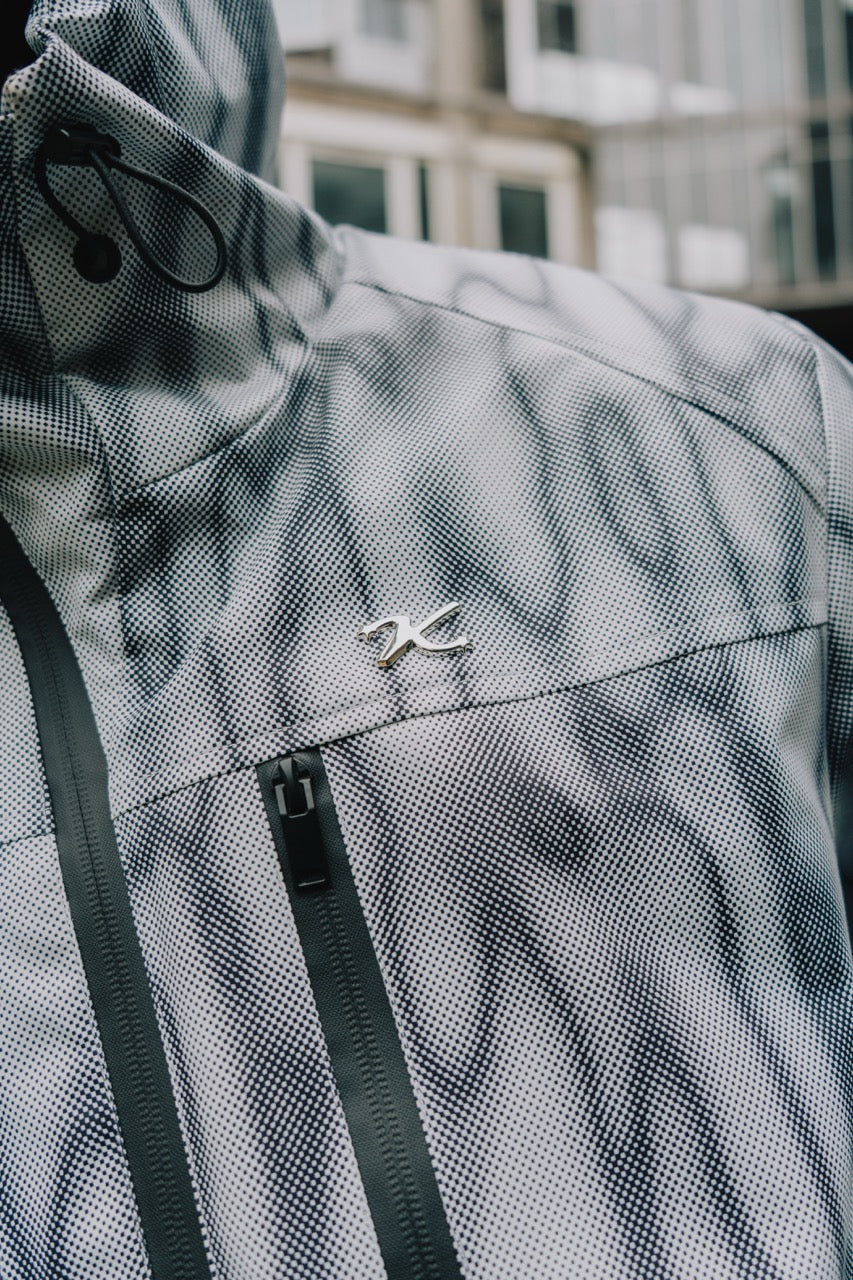 Close-up of the metal K logo pin and chest zip on the waterproof windbreaker jacket