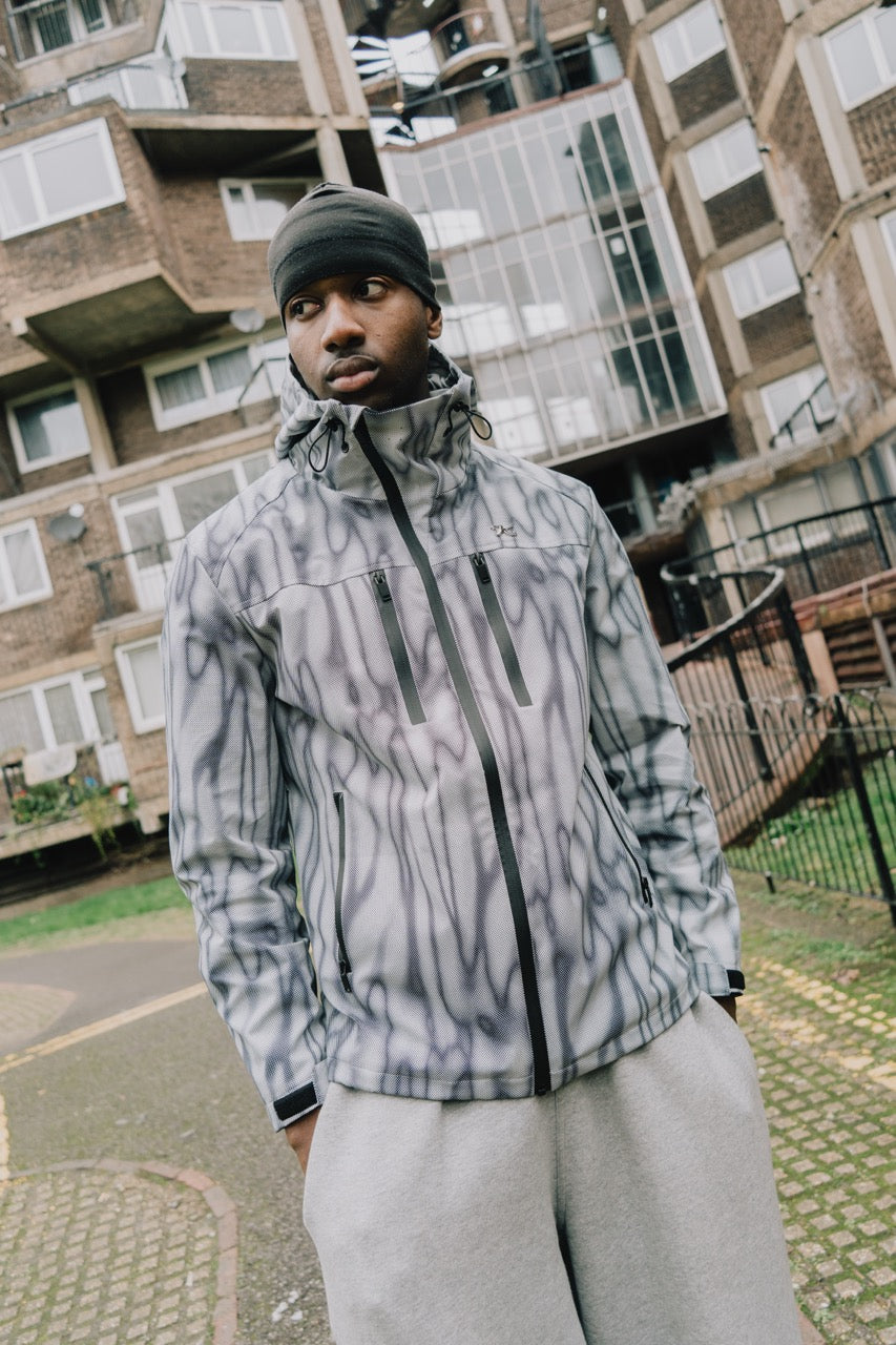 Man wearing the waterproof windbreaker jacket in a grey and white print, front view