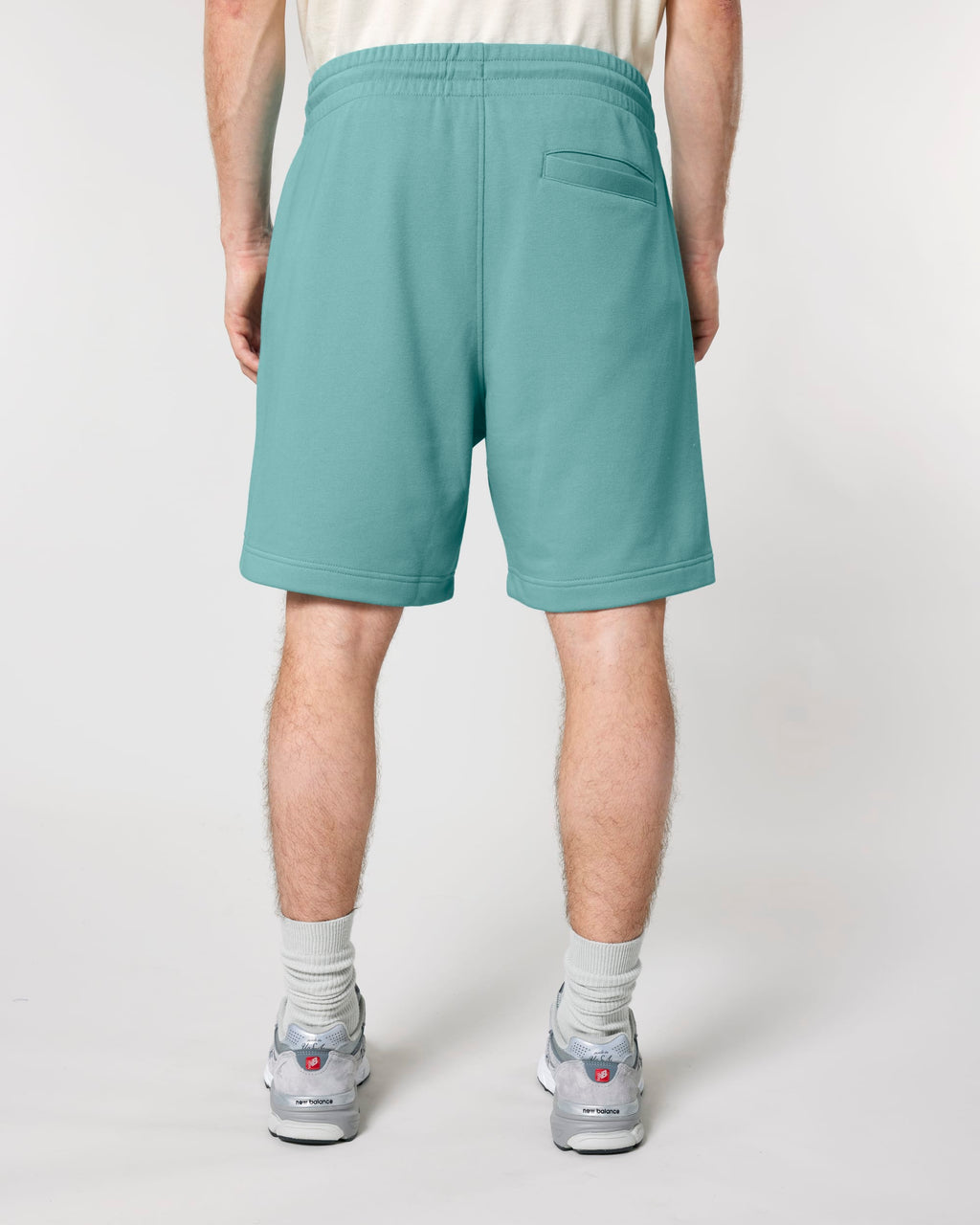 Model wearing the unisex organic cotton French terry jogger shorts in Teal Monstera, back view showing the back pocket
