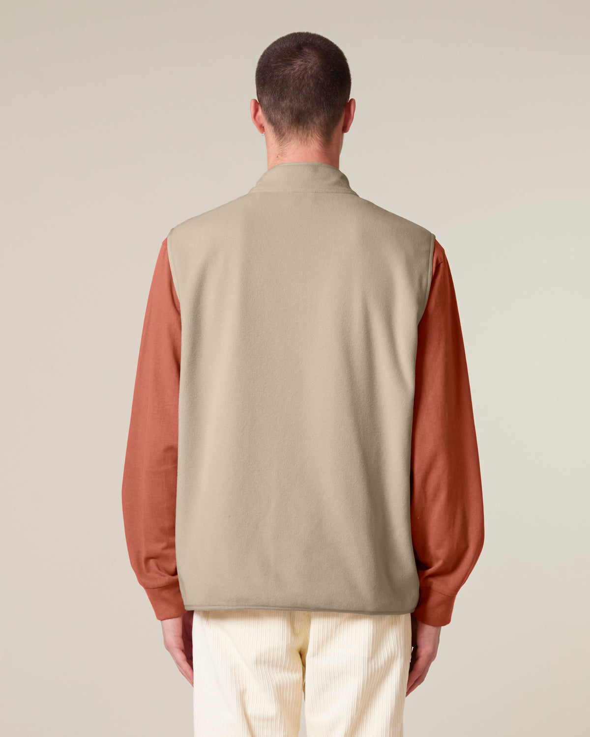 Model wearing the men's recycled fleece bodywarmer in Desert Dust, back view