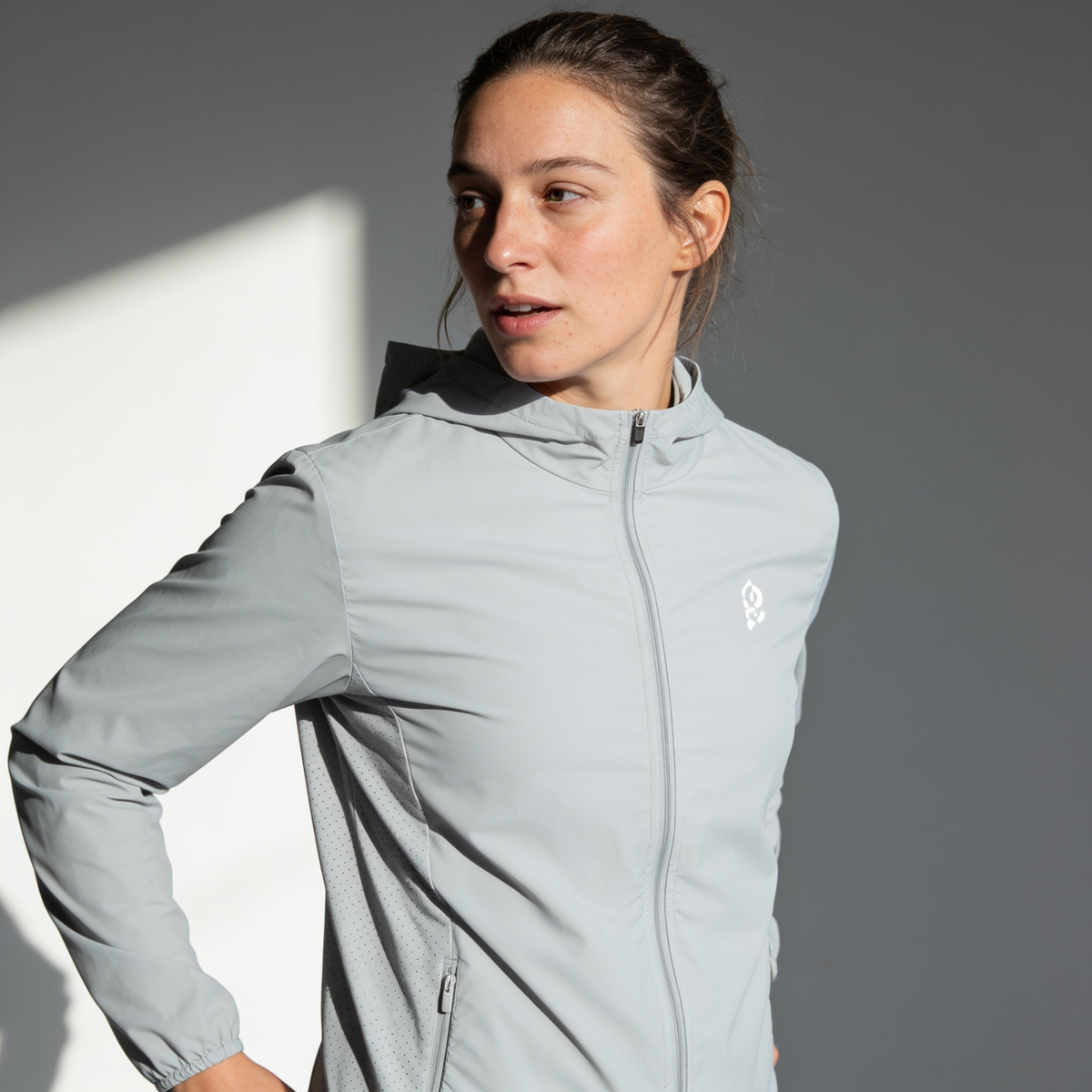 Woman wearing the unisex lightweight packable windbreaker jacket in Light Grey, front view
